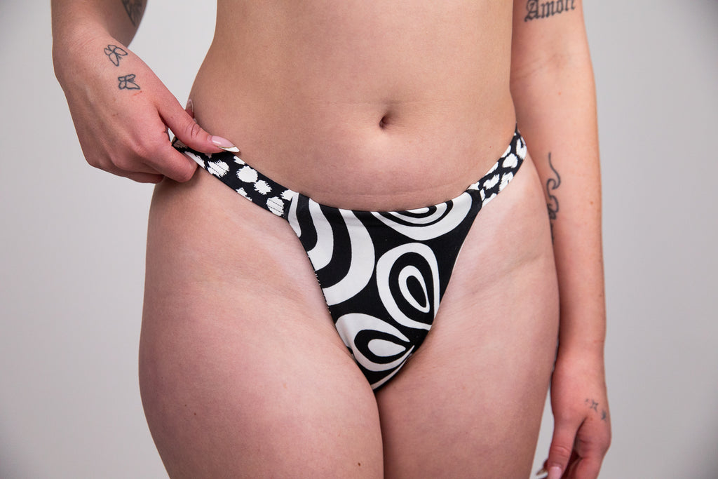 Person wearing black and white patterned underwear against a plain background