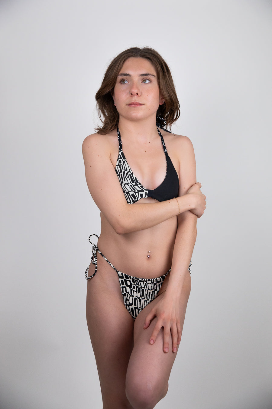 Woman wearing a black and white patterned bikini against a plain background