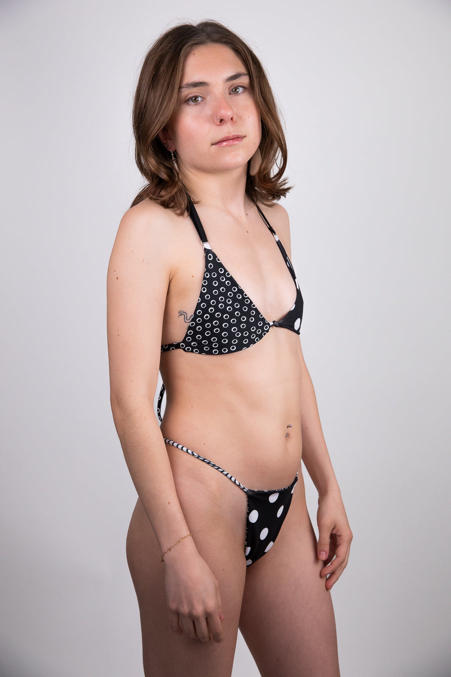 Woman wearing a black and white polka dot bikini against a plain background